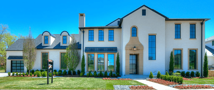 Large overview shot of the front of a huge white house with a manicured lawn.