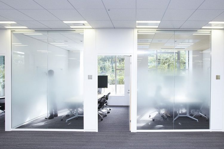 Office cubicles with privacy film on the glass partitions.