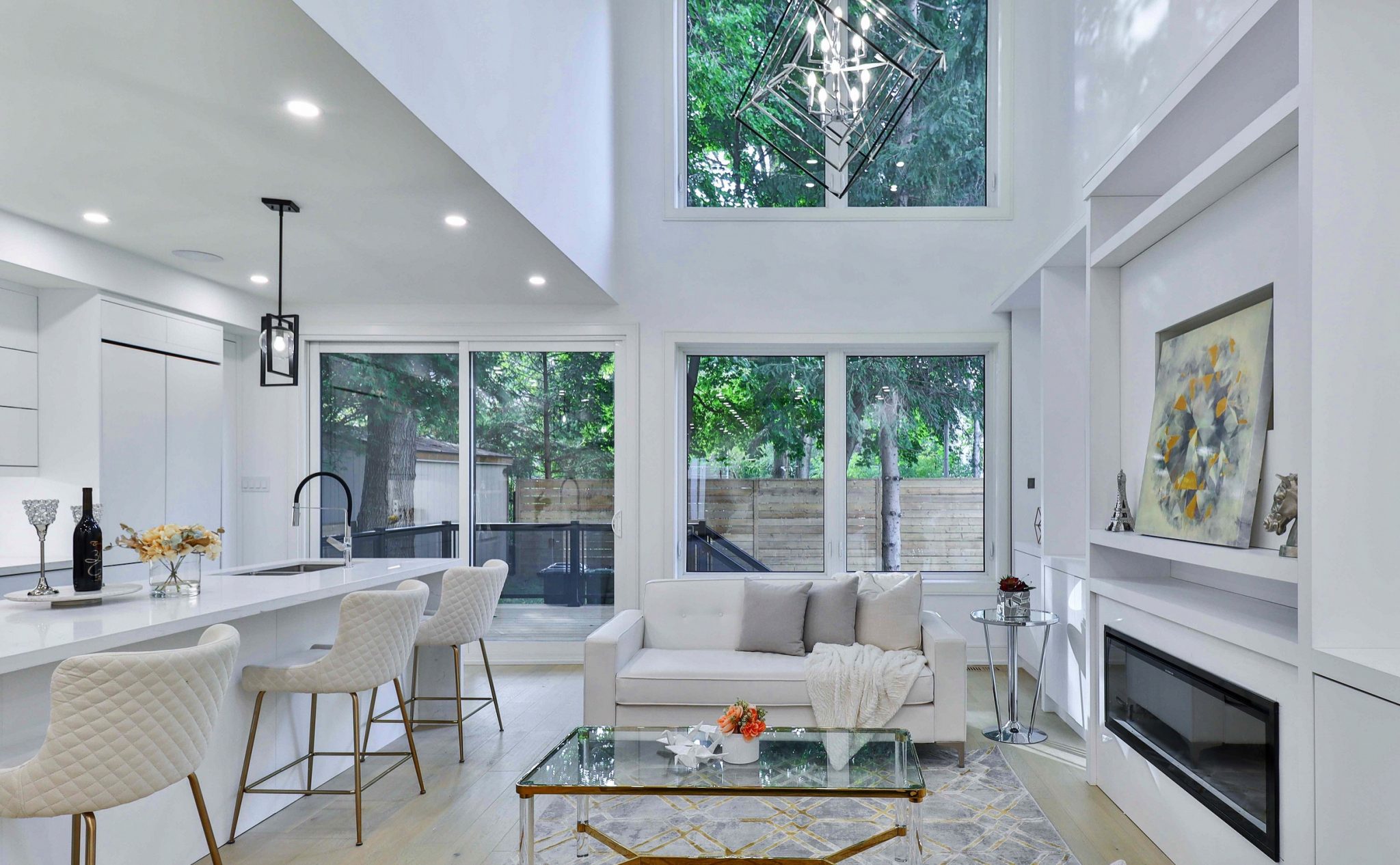 The interior of a kitchen and living room with big windows.