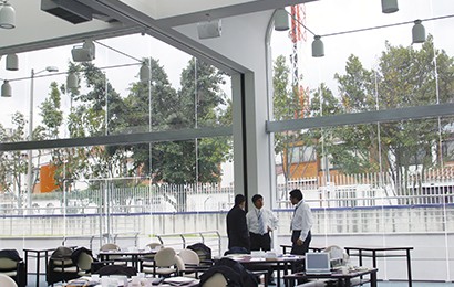 large windows in commercial building, three people in professional attire conversing.